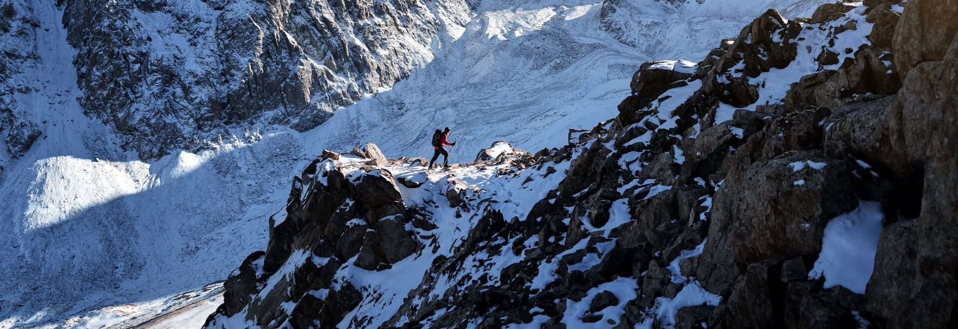 Person hiking up the side of a snow covered mountain, banner for the Explore jobs page